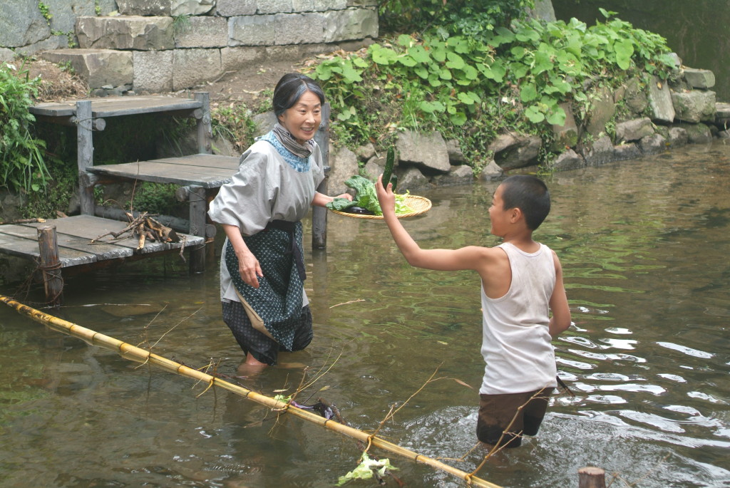 阿嬤教昭廣在河上橫放一支竹竿撈起上游漂來的蔬果